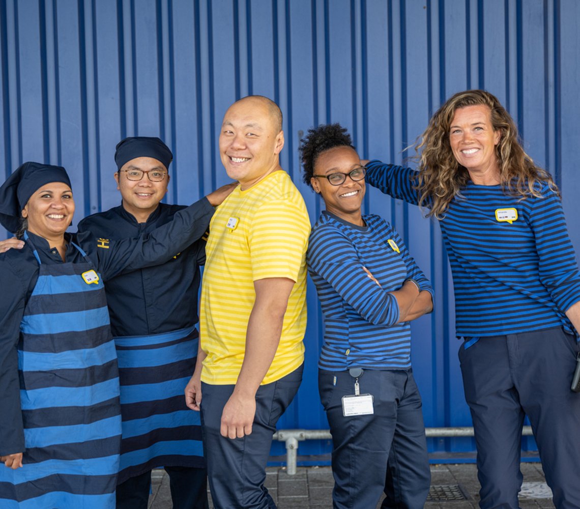 A group of IKEA co-workers smiling in front of a blue box store.