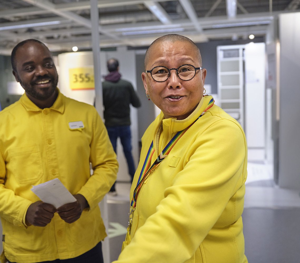 Two IKEA employees in yellow shirts smiling to the camera.