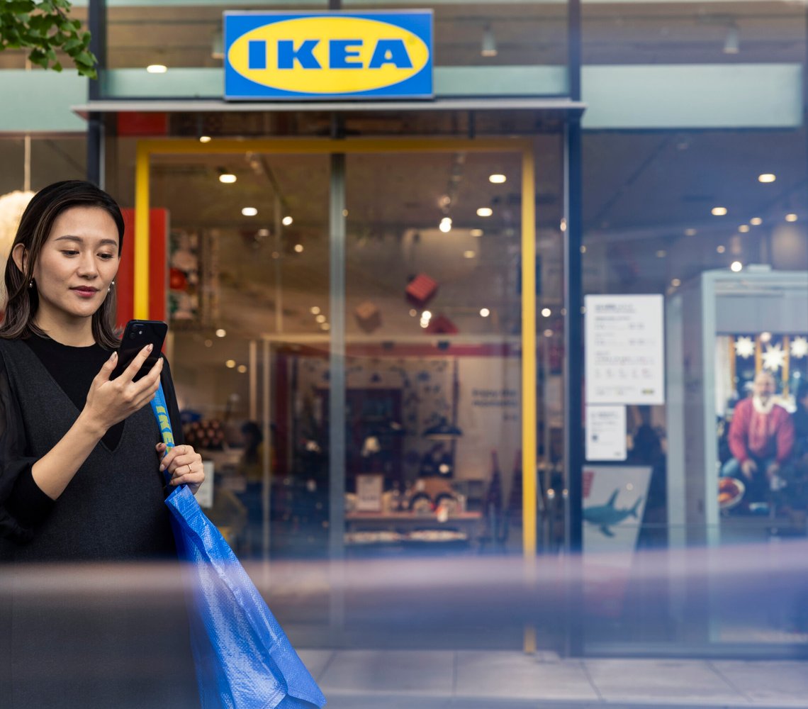Woman in front of an IKEA store looking at her phone.
