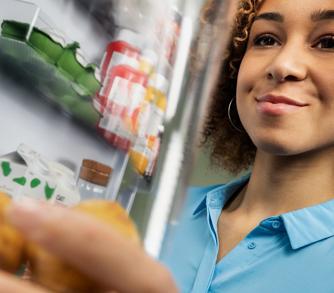Woman storing fresh food in IKEA 365+ reusable containers in refrigerator.