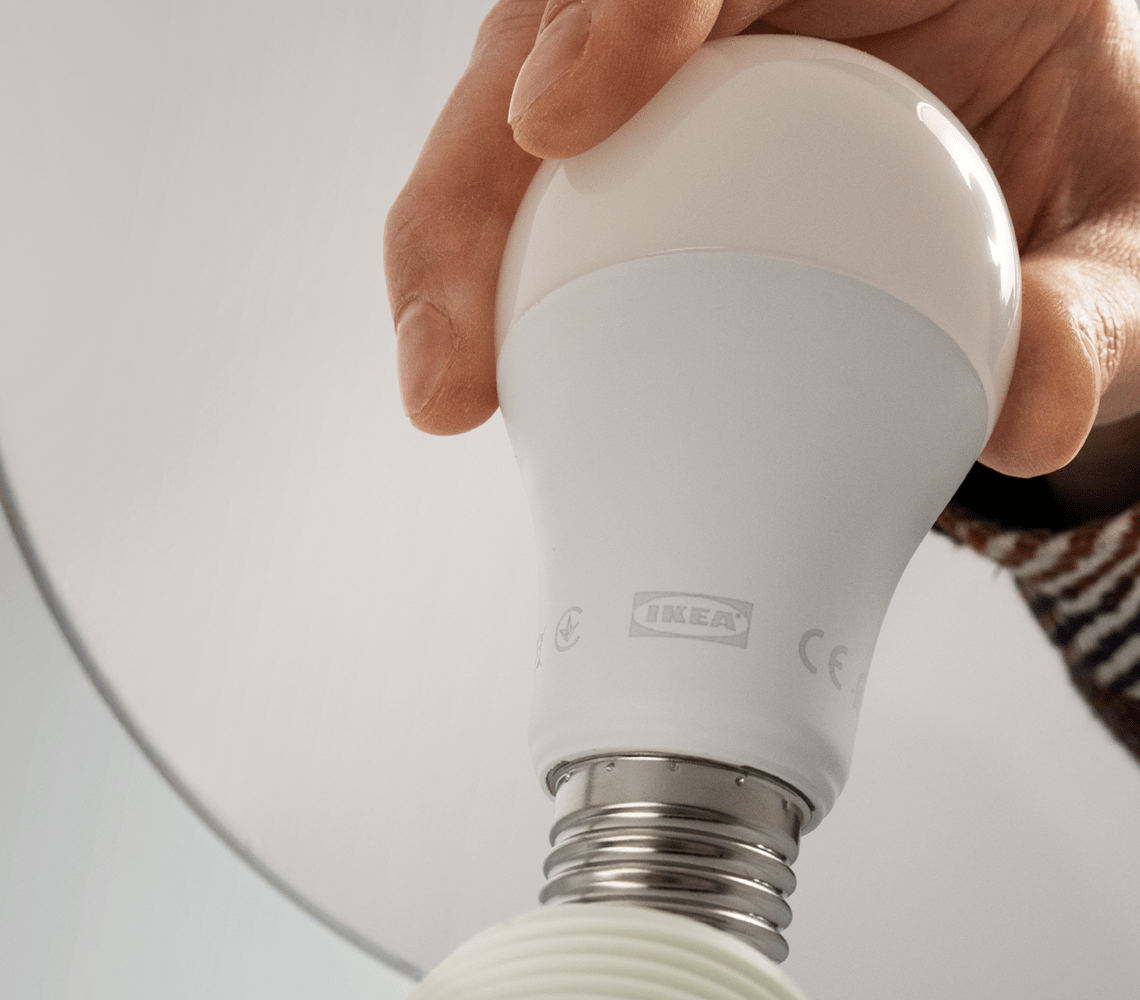 Hand holding IKEA SOLHETTA energy-efficient LED light bulb.