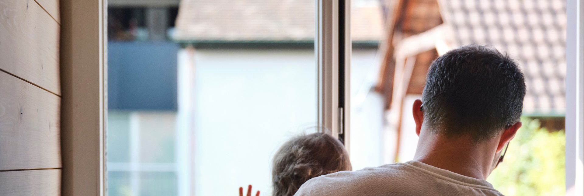 Dad holding his child in front of a window