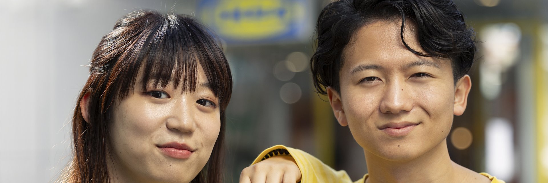 Two IKEA employees wearing yellow striped shirts and name tags, standing together outside an IKEA store.