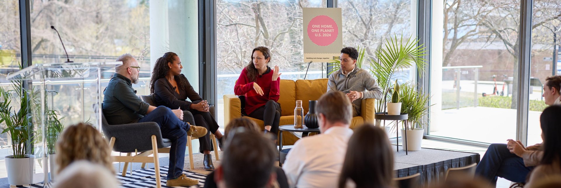 Four people having a discussion on a stage in front of a sitting audience.