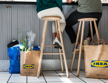 Friends sitting at a cafe with several bags from the IKEA store.