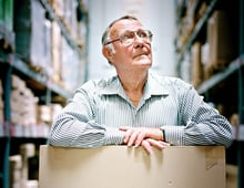 Ingvar Kamprad standing in the IKEA store ware-house with a cardboard box.