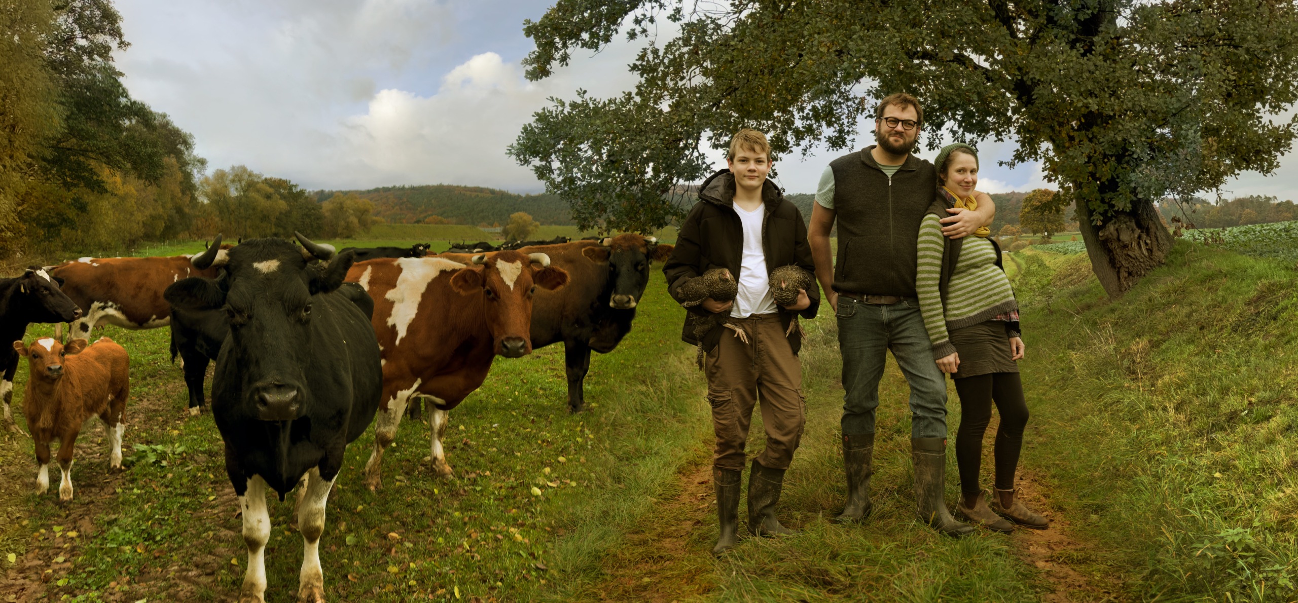 Franziska and her family standing outside next to a field with cows.