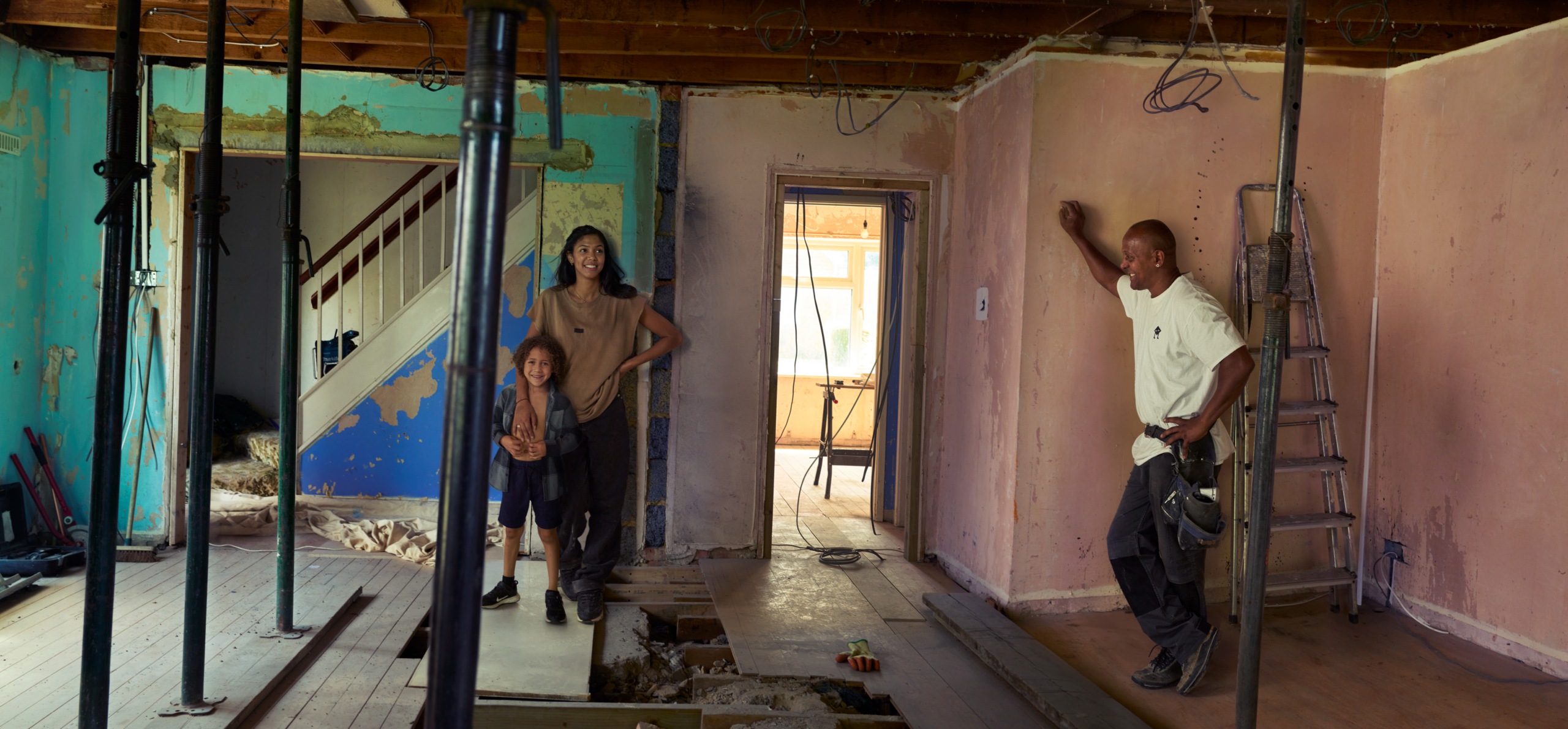 Carly, her son and a man with a tool belt is standing in the livingroom.