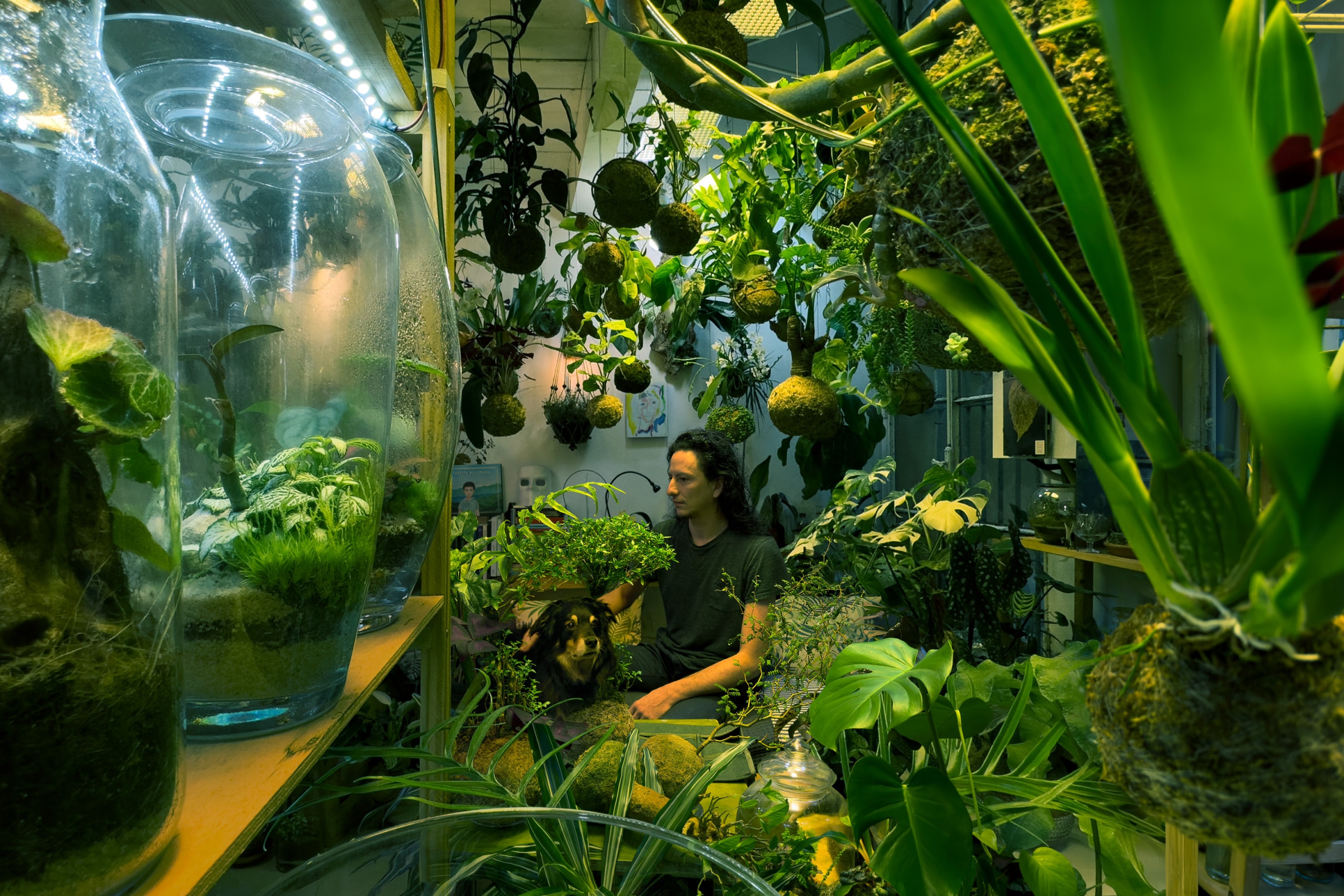 Giovanni sitting down with his dog, surrounded by plants.