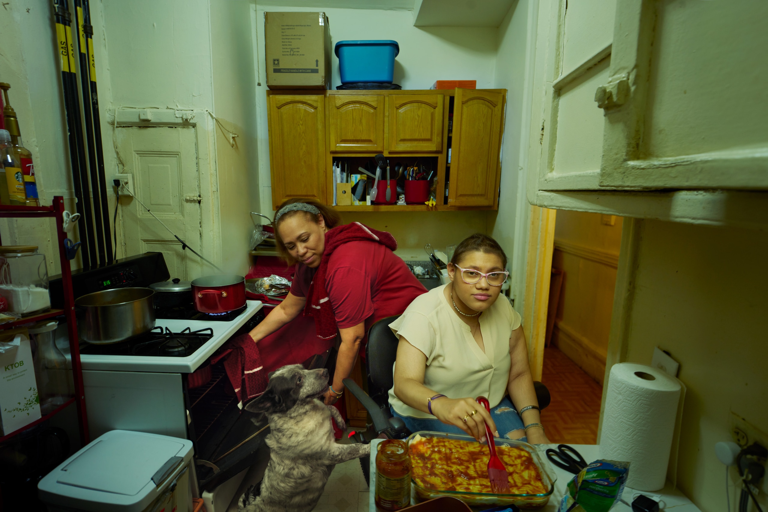 Daphne and her mother is cooking in the kitchen, their dog is standing by her side.