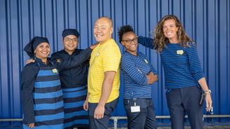 A group of IKEA co-workers smiling in front of a blue box store.