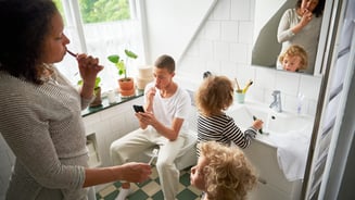Mother and three children brush teeth in bathroom.