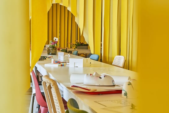 A row of chairs in a yellow room from the exhibition