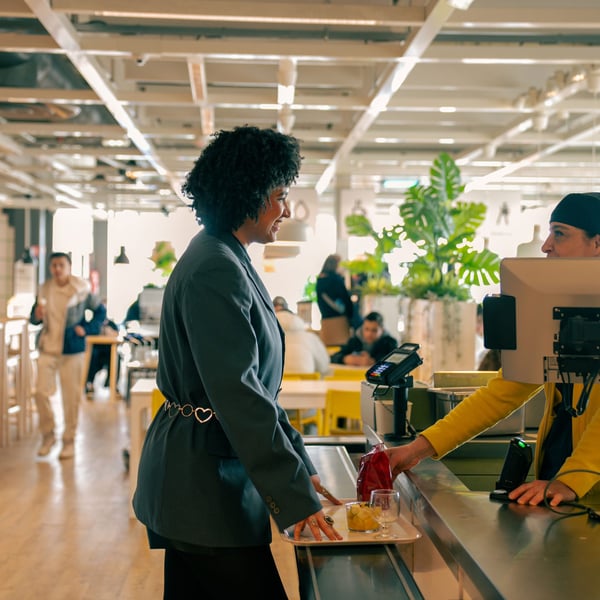 Shadia talking to a co-worker in the food check-out at the IKEA store where she works.