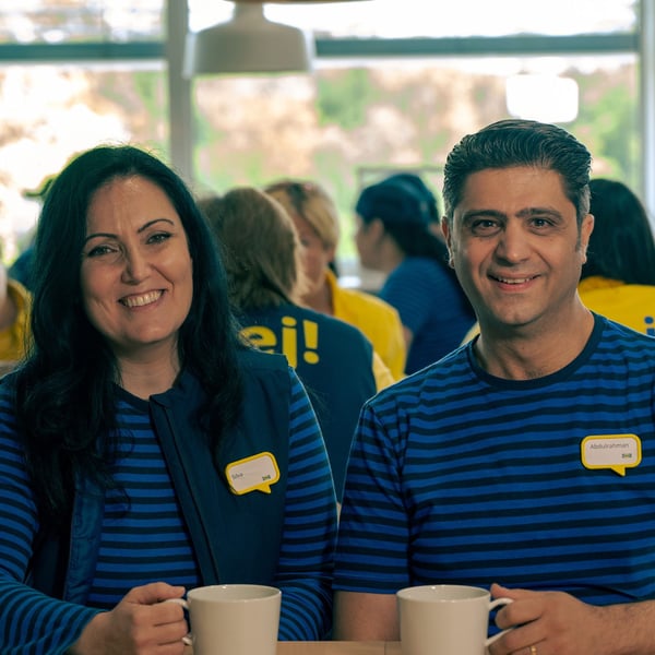 Silva and Abdul in their blue IKEA work wear sitting in the IKEA restaurant drinking coffee.