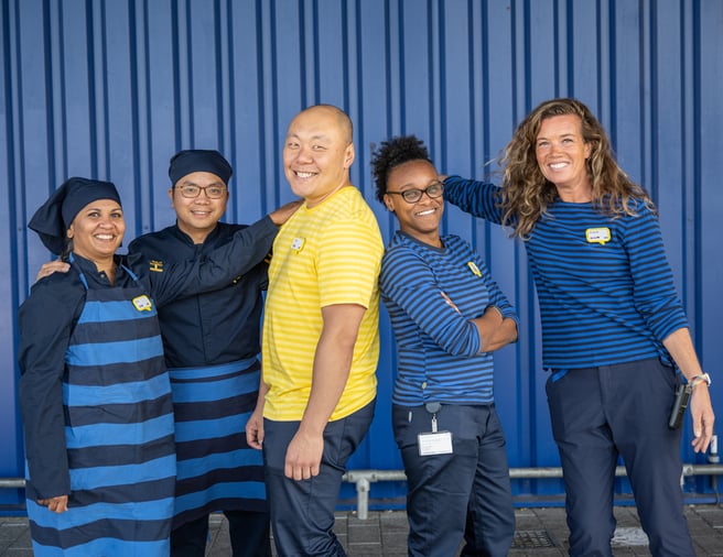 A group of IKEA co-workers smiling in front of a blue box store.
