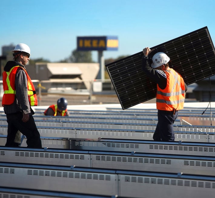 People on the roof of an IKEA store installing solar panels.
