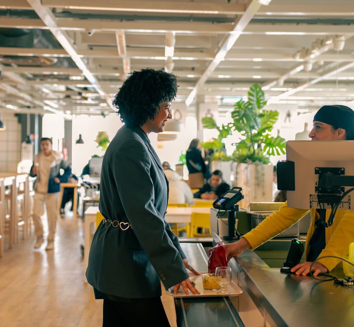 Shadia talking to a co-worker in the food check-out at the IKEA store where she works.