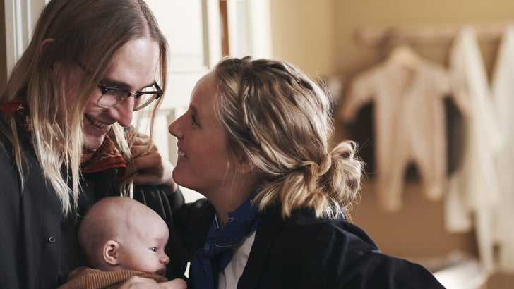 Couple look at each other while holding a baby