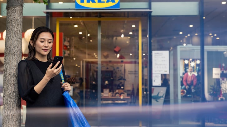 Woman in front of an IKEA store looking at her phone.