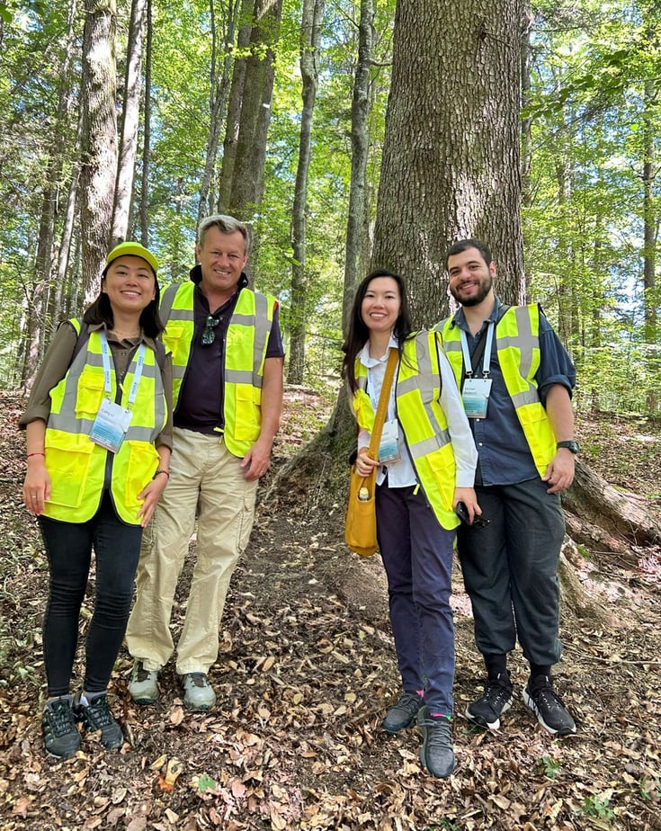Jesper Brodin, CFO of Ingka Group, standing in a forest together with three youth leaders, they all wear yellow reflective vests and smiles to the camera.