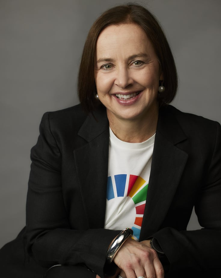 Portrait of Karen Pflug​ smiling, sitting against a grey background.