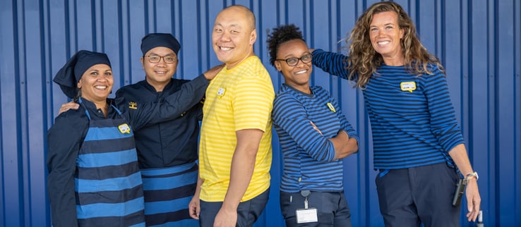 A group of IKEA co-workers smiling in front of a blue box store.