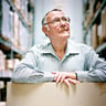 alttext Ingvar Kamprad standing in the IKEA store ware-house with a cardboard box.