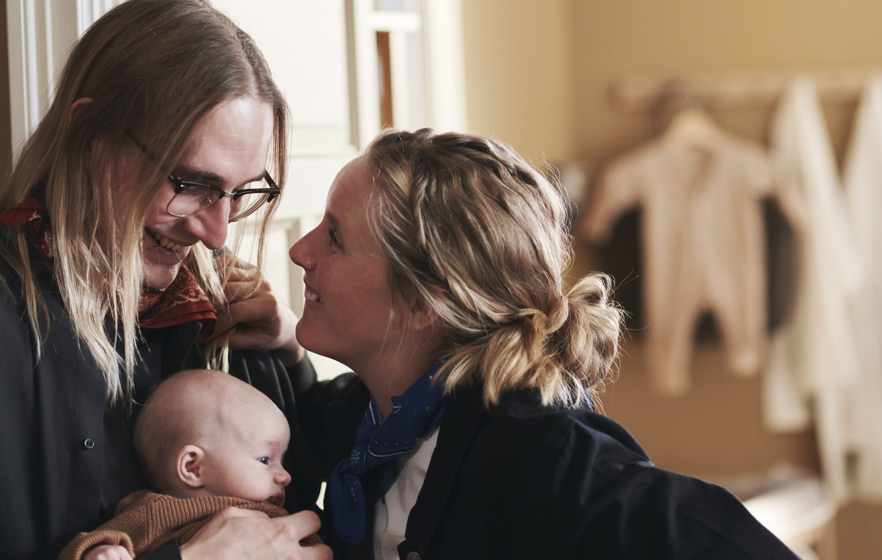 Couple look at each other while holding a baby